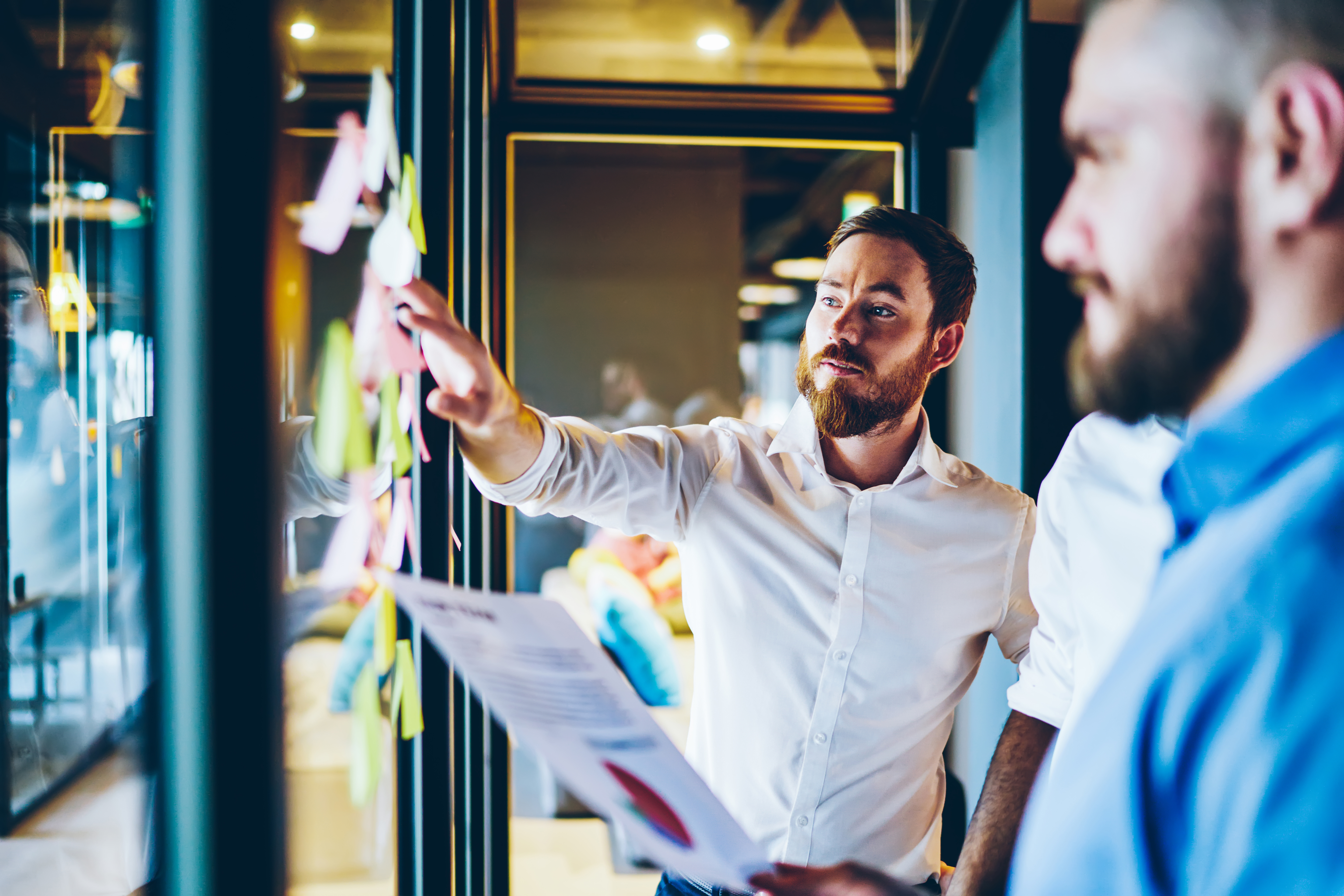 a man showing new tasks to his team colleagues in an office.