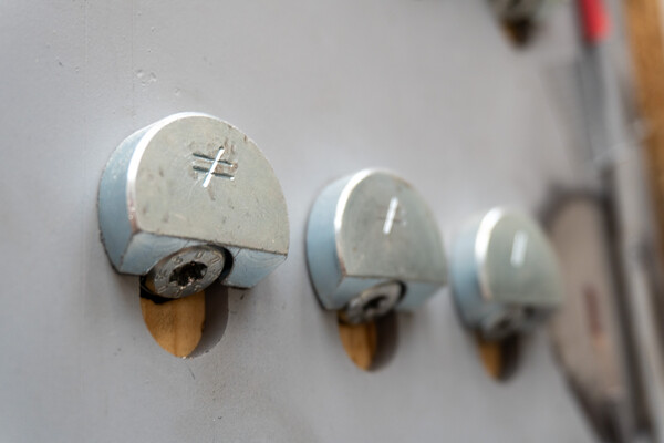 Drei ZYK Schrägverschraubungen von Simpson Strong-Tie hintereinander an einer metallenen Fläche. Jeder ist mit dem Ungleichheits-Zeichen geschmückt: ≠