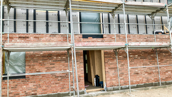 Neubau von außen. Mauerwerk erkennbar. Gerüst um das Haus.