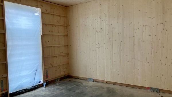 CLT Wände und Decken mit Aussparung für Tür bzw. Fenster. Verbindungsmittel, in dem Fall Winkel, auf dem Boden zu sehen.