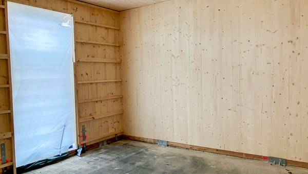 innenansicht eines Neubau Projekts mit CLT. Man sieht die Lücke für die Tür und die Winkelverbinder, die Boden und Wand miteinander verbinden.