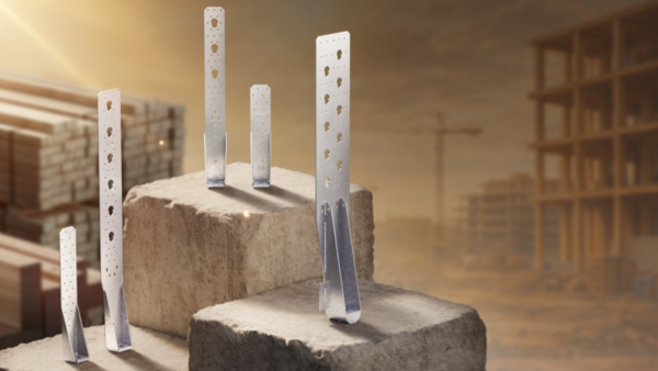 Eine gelbliche Landschaft mit Hochhaus-Baustellen und Kränen im Hintergrund; von links oben scheint die Sonne ins Bild. Im Vordergrund ein Stapel Holzbalken und mehrere Betonblöcke, auf denen verschiedene Zuganker stehen. Genau in der Mitte des Bildes ist der größte Zuganker: ein längliches Stahl-Bauelement mit einer Rückenplatte voller Anschlusslöcher sowie einer Halbrundscheibe in einer runden Aufnahme am Boden.