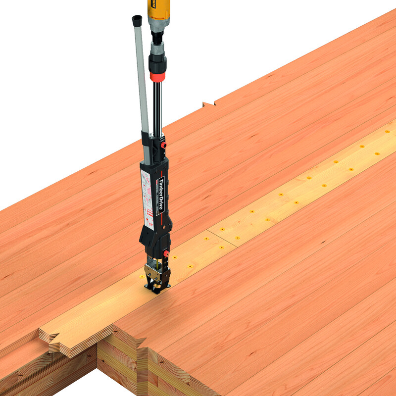 Eine dicke, mehrschichtige Holzplatte von rötlicher Farbe (Brettsperrholz), diagonal, füllt die unteren zwei Drittel des Bildes aus. Unten links ist eine Ecke zu sehen, an der kein Holz ist, hier sind die Schichten im Inneren sichtbar. Ein Timber Drive kommt, aufrecht stehend, von oben links ins Bild und befestigt eine Holzleiste an der Brettsperrholz-Platte. Hinter dem Gerät und nach oben rechts führend sind zwei Reihen bereits in die Leiste eingedrehter Schrauben.
