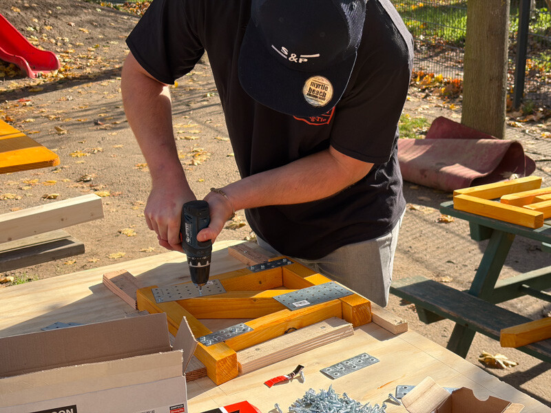 Mann schraubt an einem Holz herum. 
