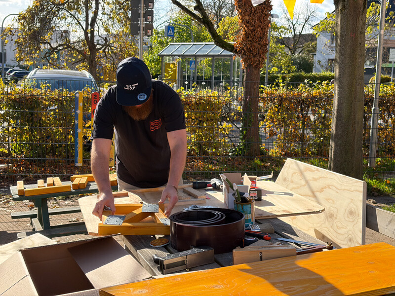 Mann schraubt an Holz herum.