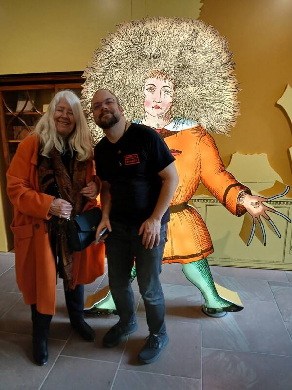 Ein Mann und eine Frau stehen vor einer Struwwelpeter-Figur. 